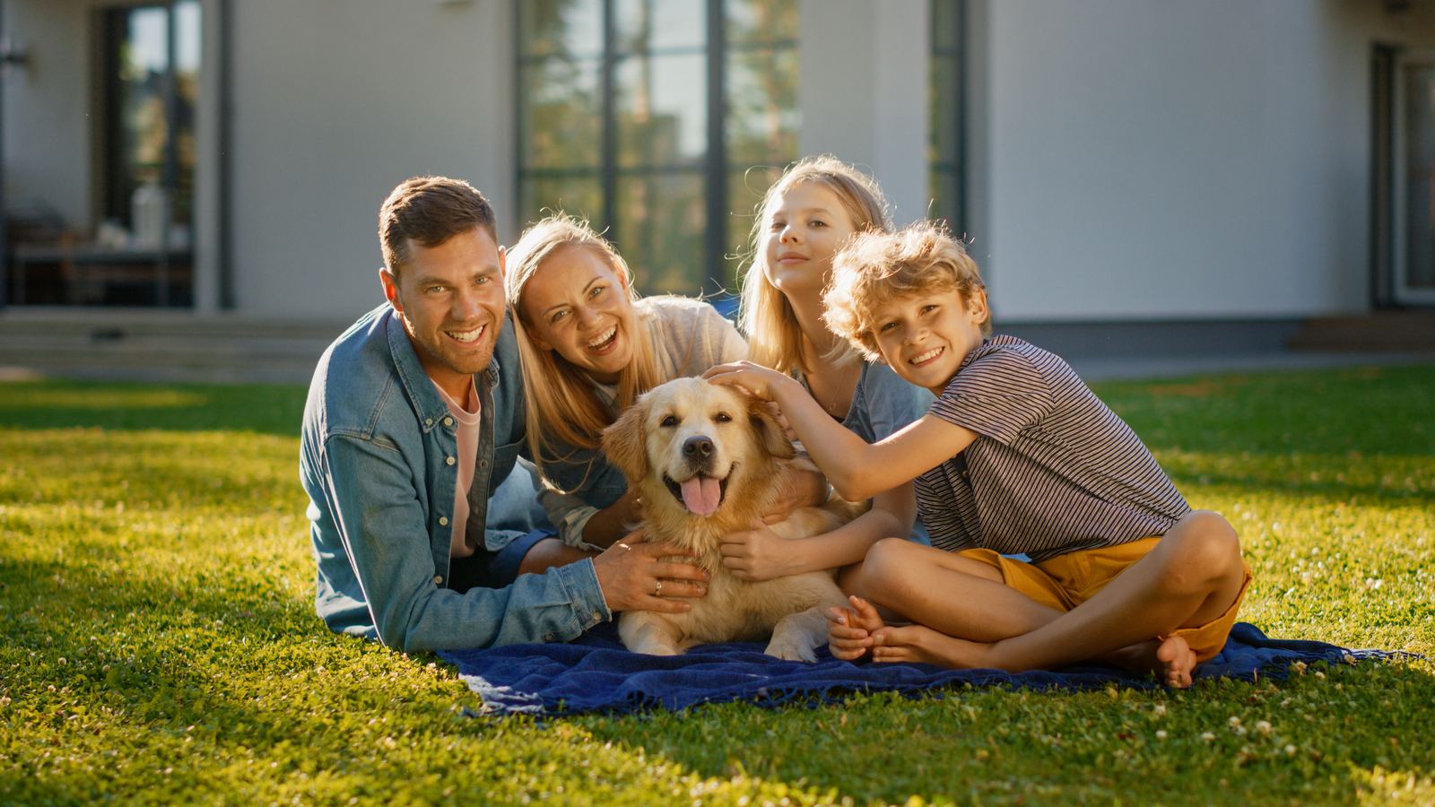 Family with their golden retriever in a sunny backyard.
