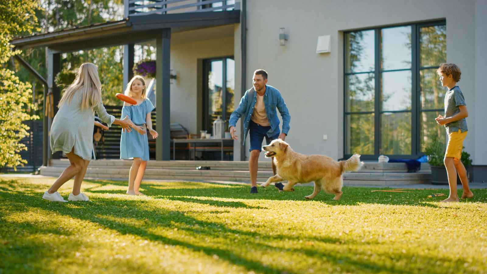 A happy dog mid-leap catching a frisbee in a sunny backyard — the kind of yard a PooPartner keeps spotless.